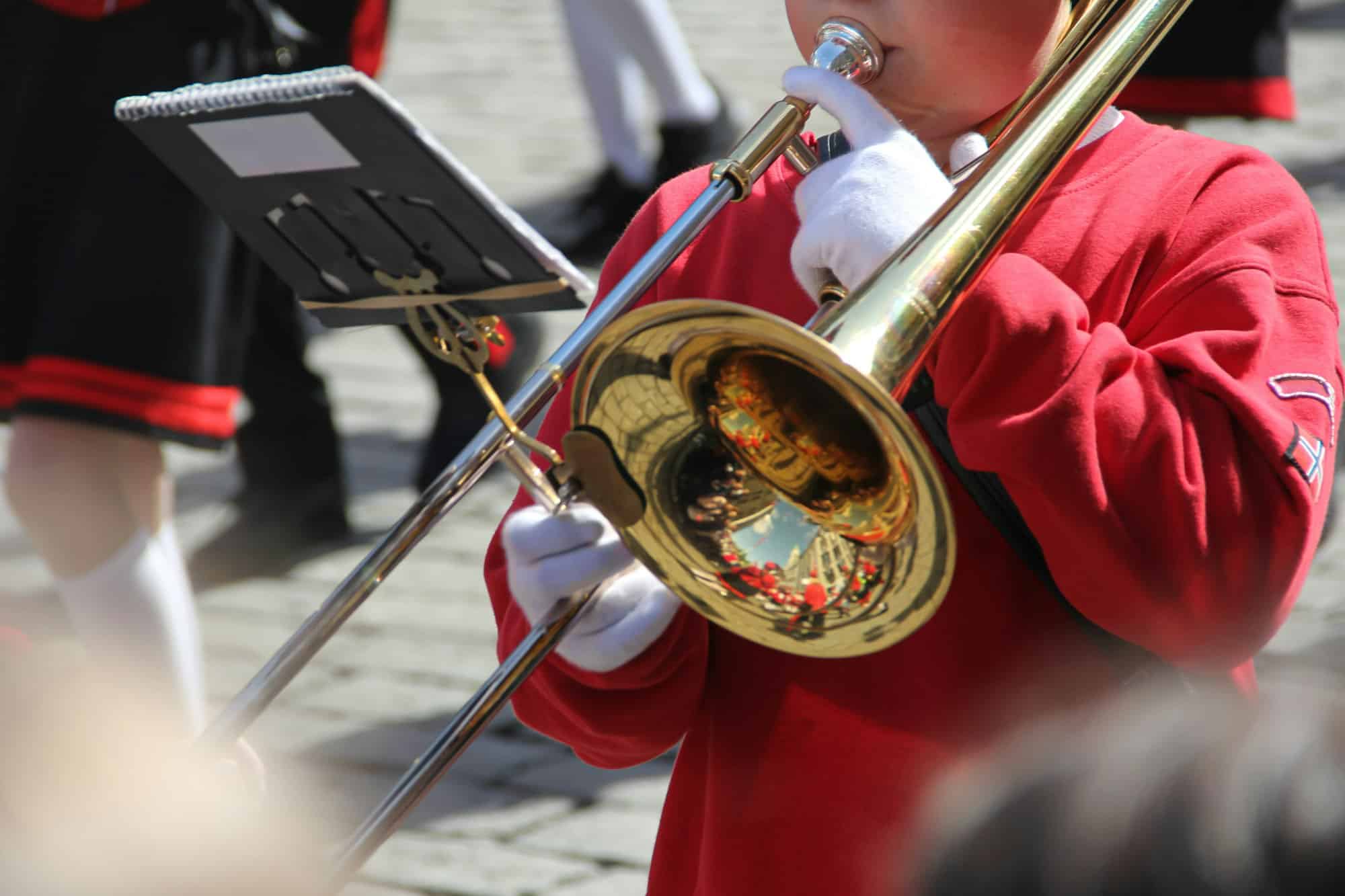 Gen Z male playing a trombone during 17 May Norwegian Constitution day parade celebration.